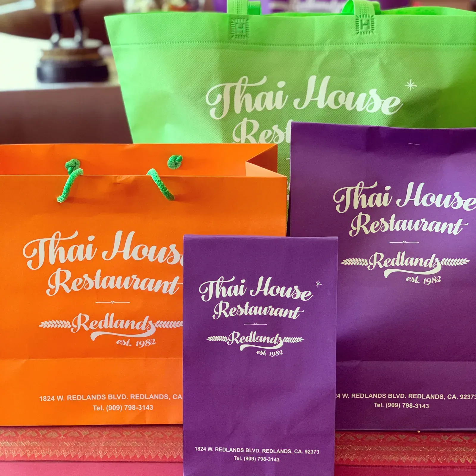 Thai House Redlands catering bags in purple, orange, and green ready for pickup