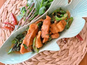 Fried catfish fillet simmered in Thai House red curry sauce on a plate