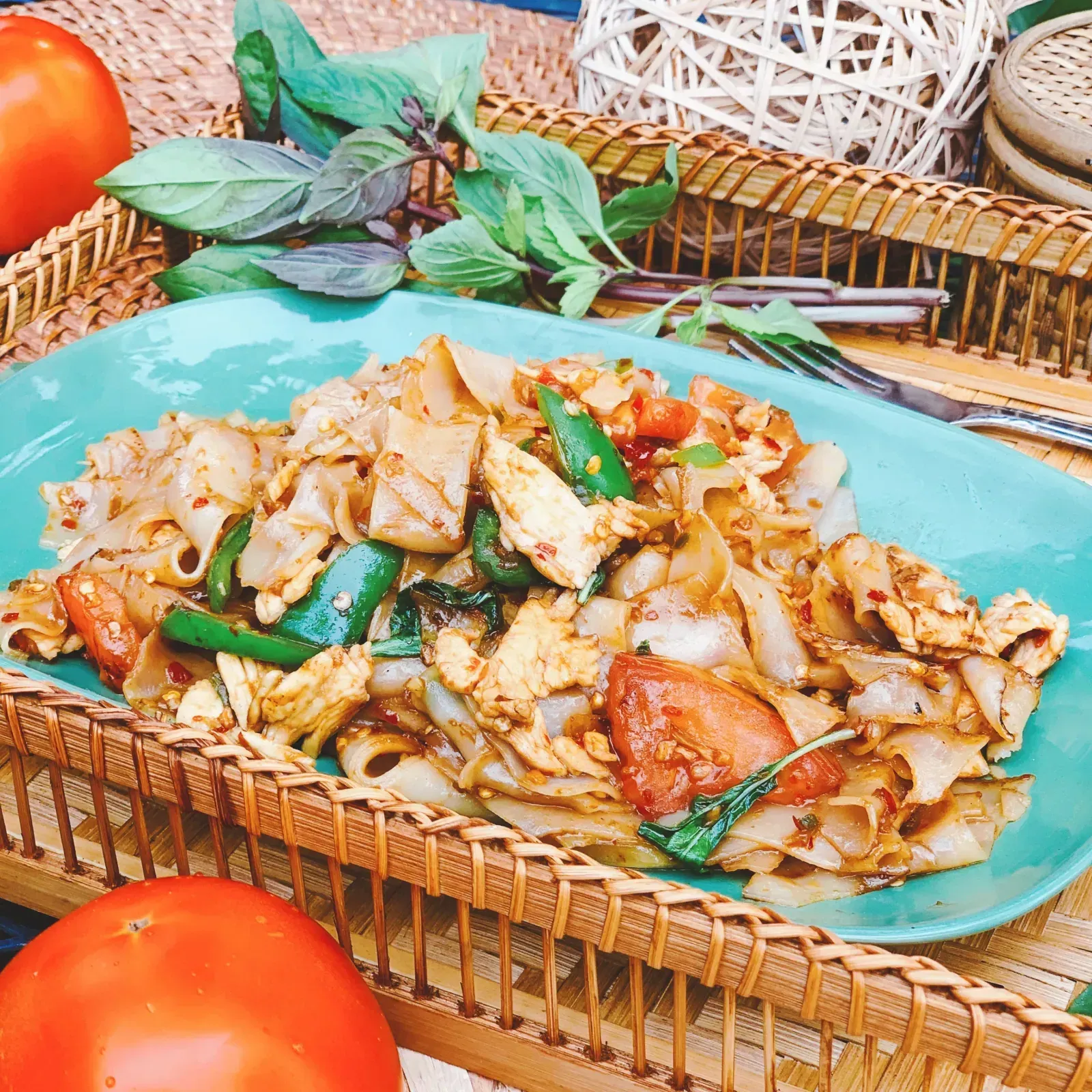 Spicy drunken noodles stir-fried with tomatoes, onions, chili and fresh Thai basil