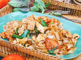 Spicy drunken noodles stir-fried with tomatoes, onions, chili and fresh Thai basil