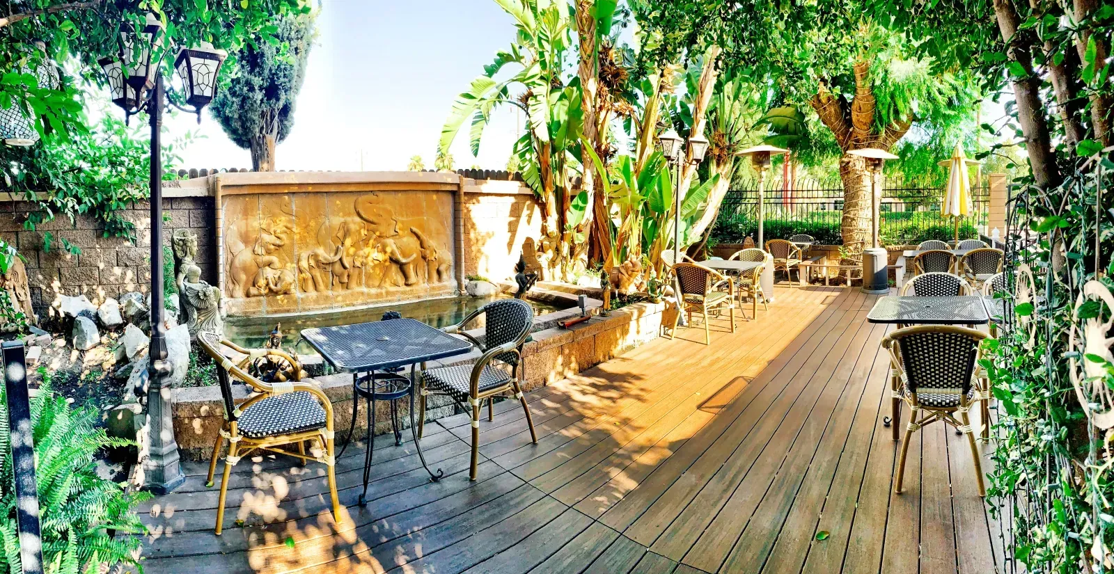 Thai House Redlands garden patio with elephant fountain, banana trees, and bistro seating