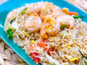 Thai shrimp fried rice with scallions, onions, tomatoes and egg on a plate