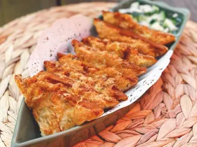 Golden fried Thai toast triangles topped with ground chicken and shrimp on a plate