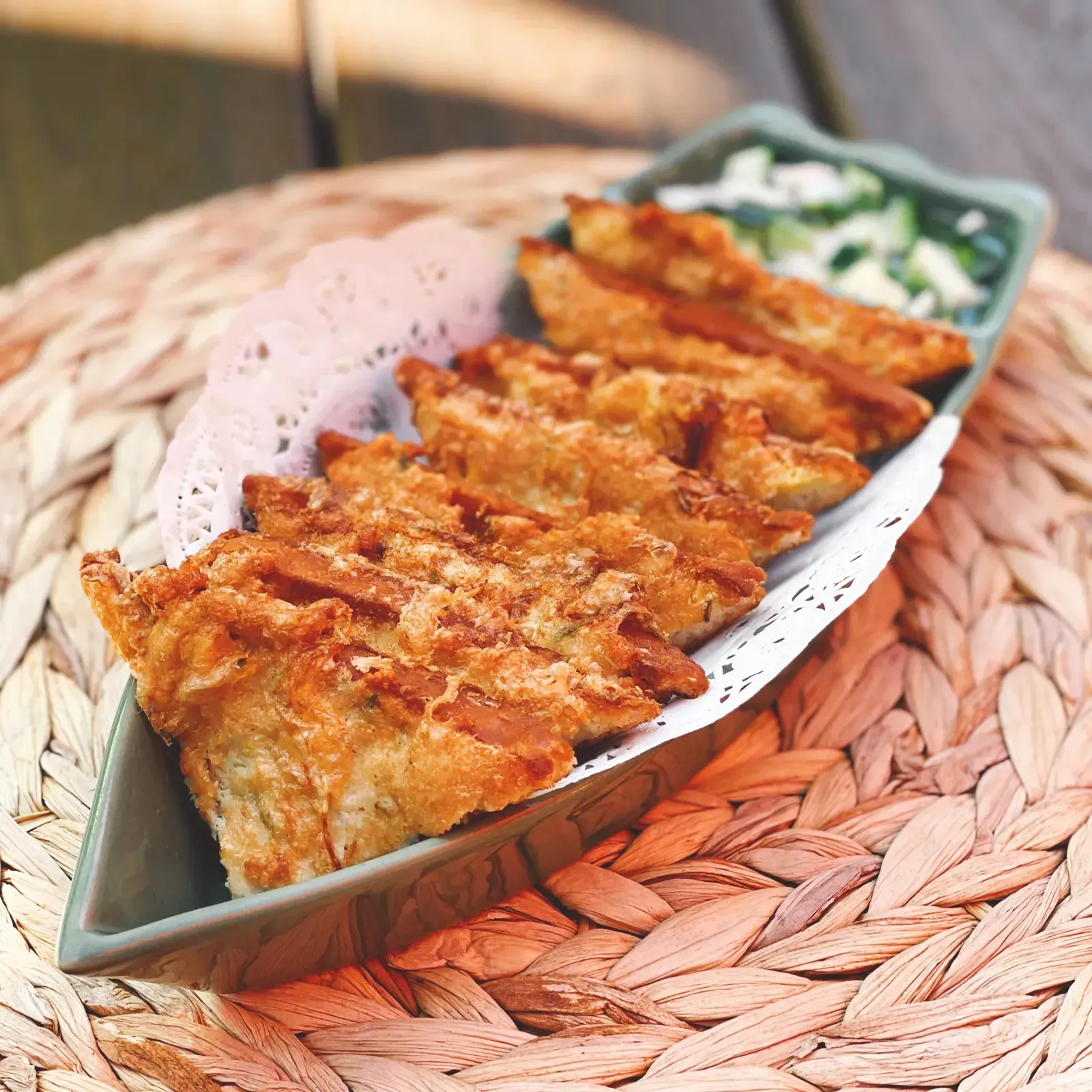 Golden fried Thai toast triangles topped with ground chicken and shrimp on a plate